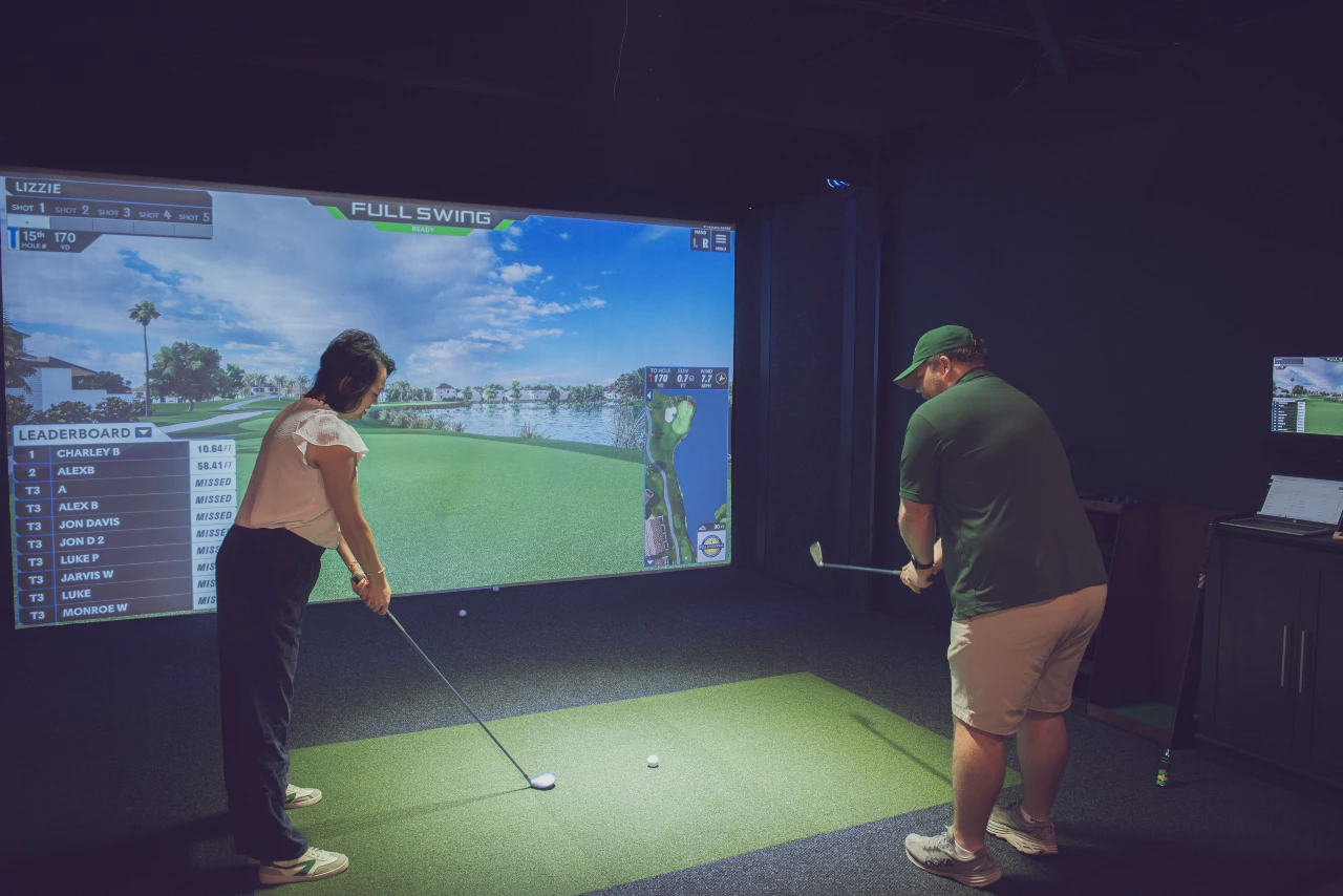 Golfers competing on a simulator at Swing Away Golf Club in Birmingham, Alabama