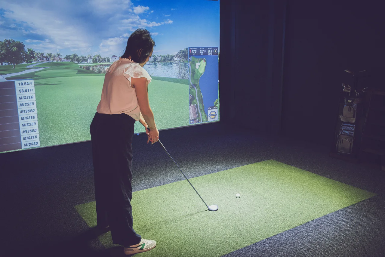 Golfer addressing the ball in front of the simulator screen